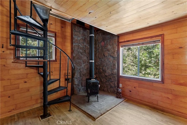 interior space featuring wood-type flooring, wood ceiling, a wood stove, and wood walls