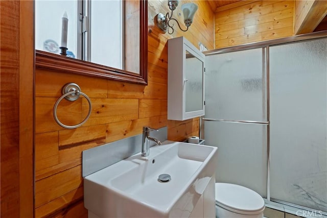 bathroom featuring an enclosed shower, vanity, toilet, and wooden walls