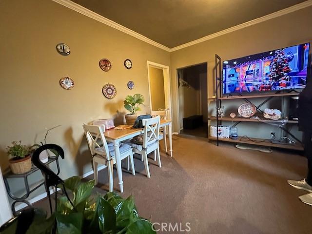 carpeted dining room featuring ornamental molding