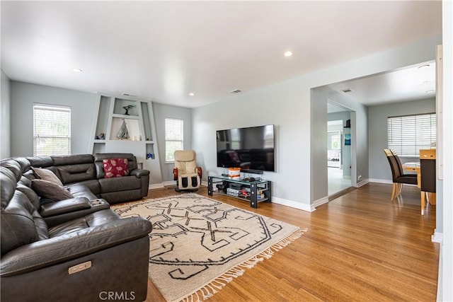 living room featuring plenty of natural light, wood-type flooring, and built in shelves