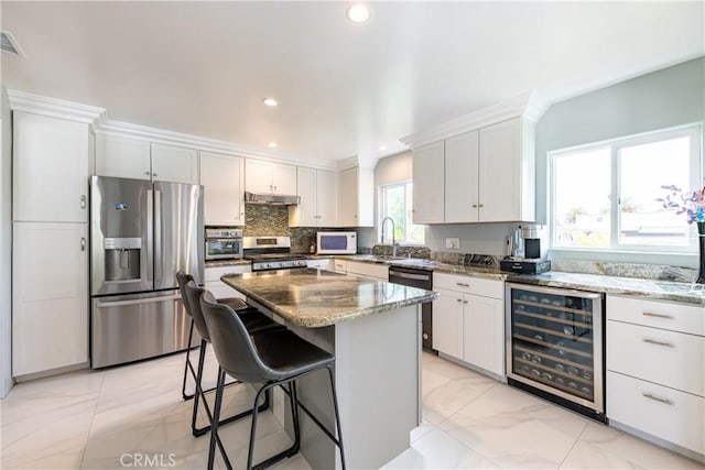 kitchen featuring wine cooler, appliances with stainless steel finishes, white cabinetry, and a kitchen island