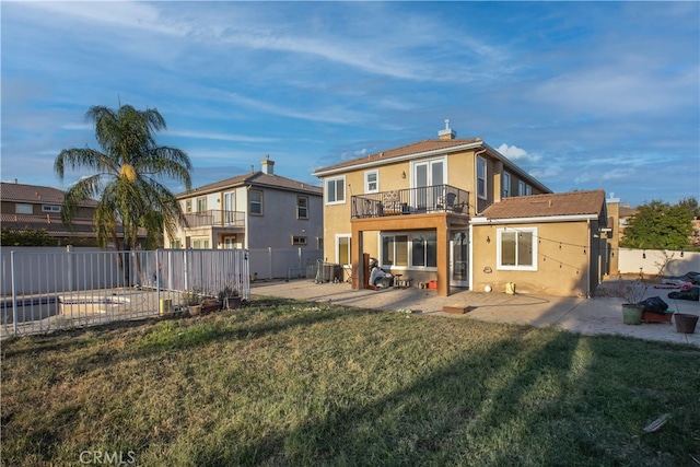 back of property with a patio, a yard, and a balcony