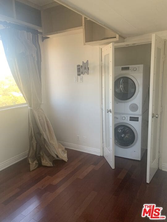 clothes washing area with stacked washer and dryer and dark wood-type flooring