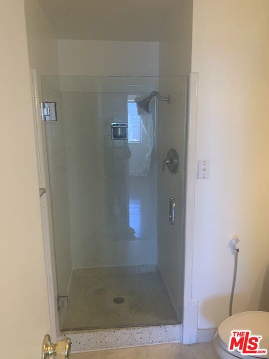 bathroom with tile patterned flooring, an enclosed shower, and toilet