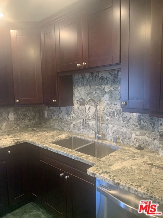 kitchen with tasteful backsplash, light stone counters, sink, and stainless steel dishwasher