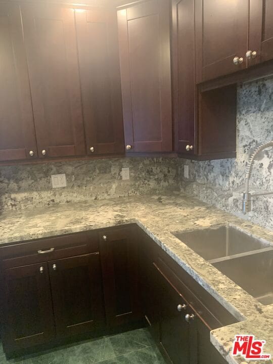 kitchen featuring tasteful backsplash, light stone countertops, and sink