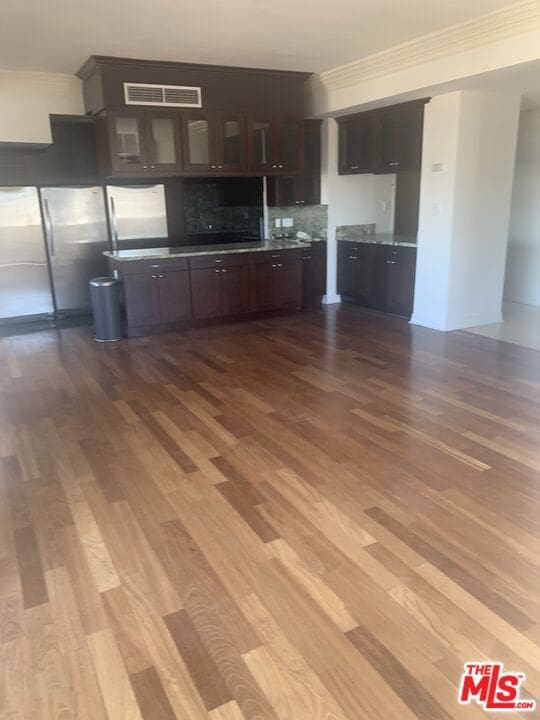 kitchen with stainless steel refrigerator, tasteful backsplash, light hardwood / wood-style flooring, crown molding, and dark brown cabinets