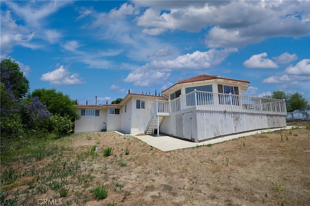 rear view of property featuring a wooden deck and a patio area