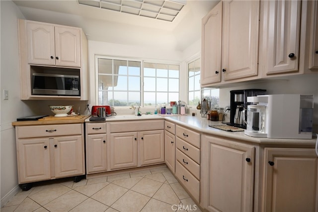 kitchen with sink, light tile patterned flooring, and stainless steel microwave