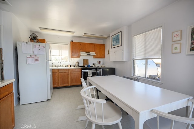 kitchen featuring white fridge, plenty of natural light, and stainless steel electric range oven