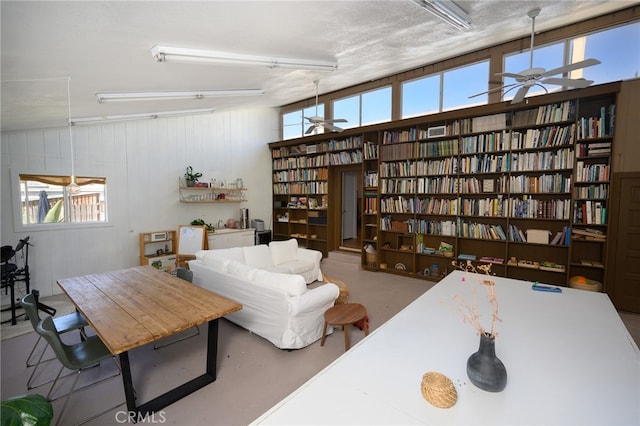 sitting room featuring ceiling fan, lofted ceiling, a wealth of natural light, and concrete flooring