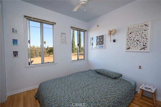 bedroom featuring ceiling fan, multiple windows, and hardwood / wood-style floors