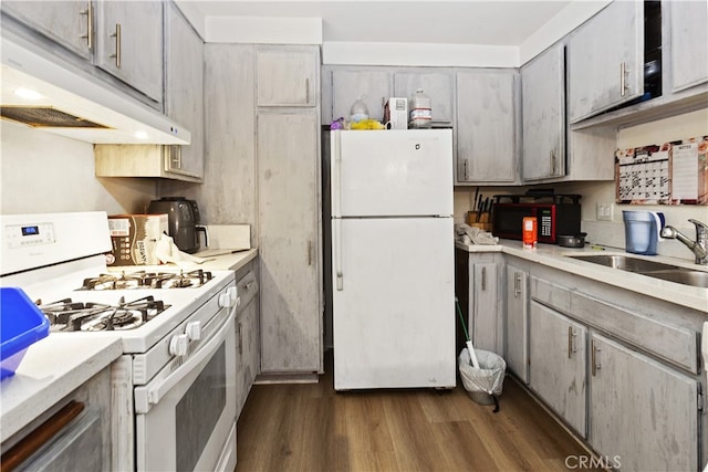 kitchen with gray cabinetry, white appliances, dark wood-type flooring, and sink