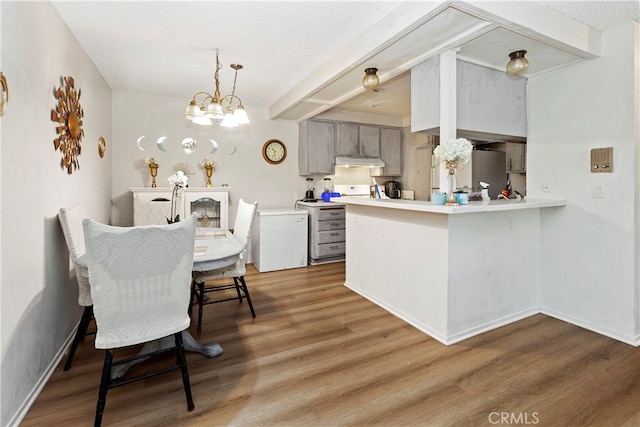 kitchen featuring wood-type flooring, a textured ceiling, kitchen peninsula, gray cabinetry, and an inviting chandelier