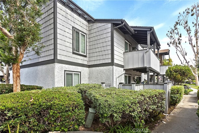 view of side of property with stucco siding and a balcony