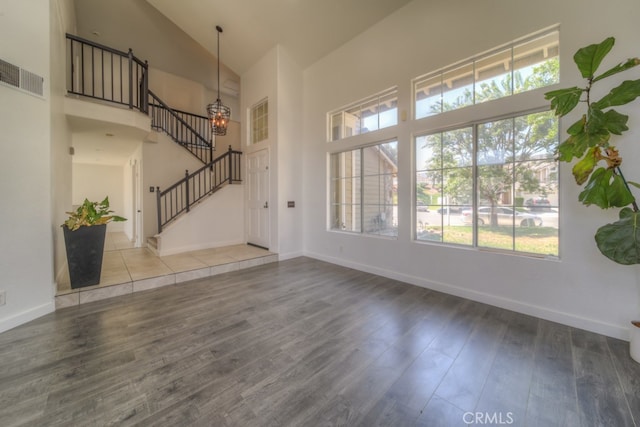 unfurnished living room with high vaulted ceiling, a wealth of natural light, and hardwood / wood-style flooring