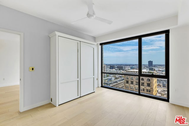 bedroom with ceiling fan, light hardwood / wood-style floors, and a closet