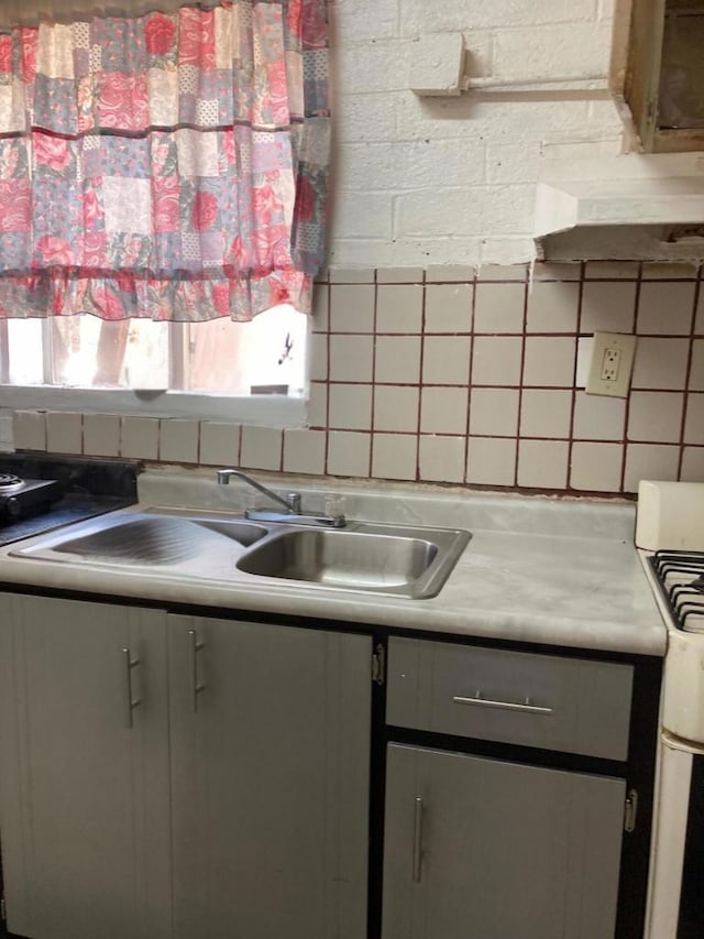 kitchen with gray cabinets, decorative backsplash, sink, and white gas range oven