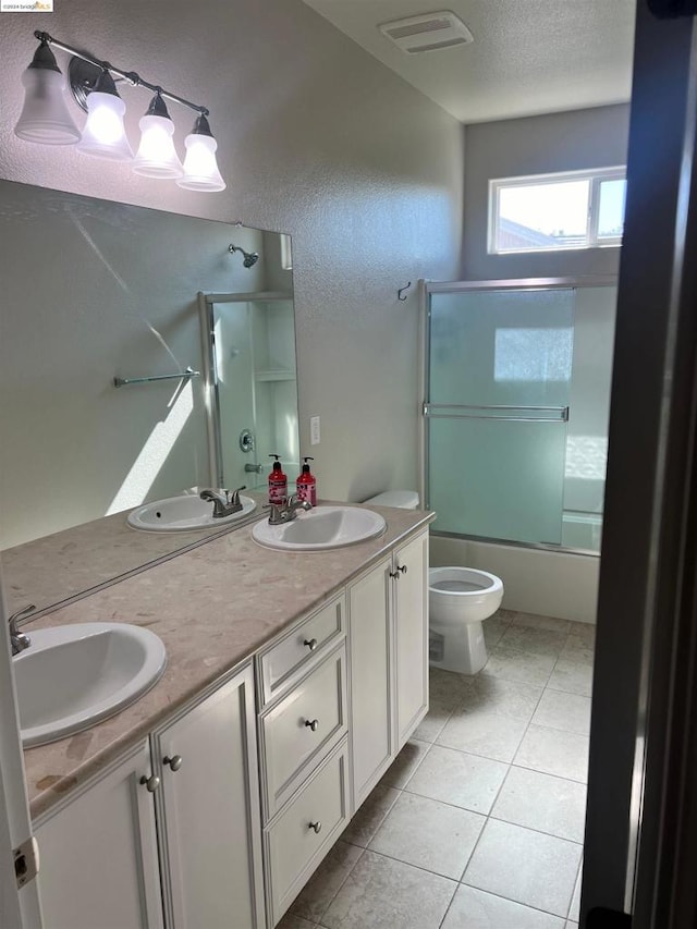 full bathroom with vanity, a textured ceiling, bath / shower combo with glass door, tile patterned floors, and toilet