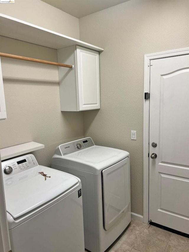 washroom with cabinets, washing machine and dryer, and light tile patterned flooring