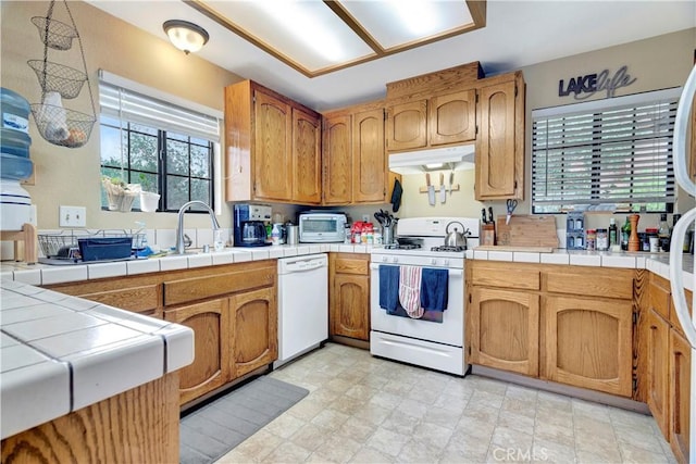 kitchen with tile countertops, white appliances, and sink