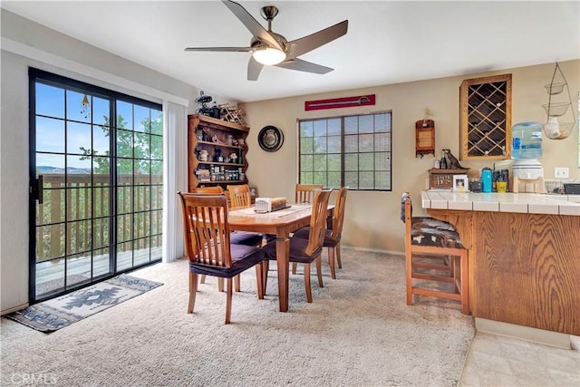 carpeted dining space featuring bar area and ceiling fan