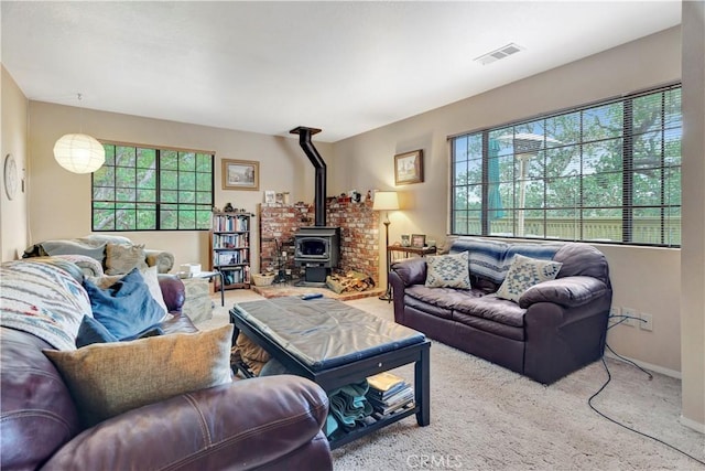 carpeted living room with a wood stove and a wealth of natural light