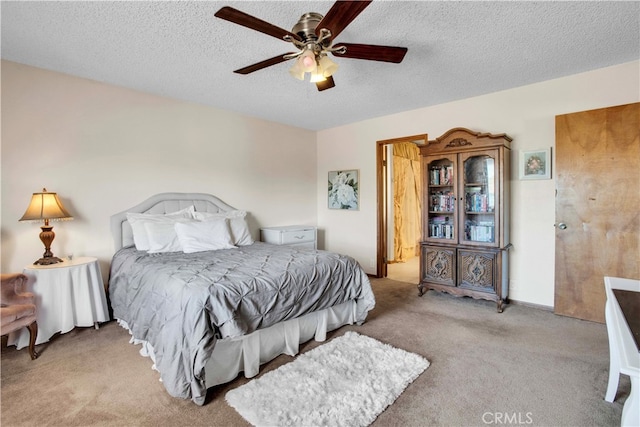 carpeted bedroom with ceiling fan and a textured ceiling