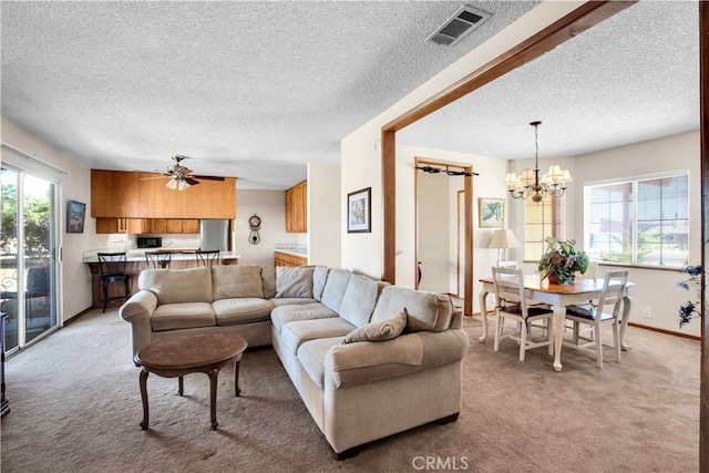 carpeted living room with a textured ceiling and ceiling fan with notable chandelier