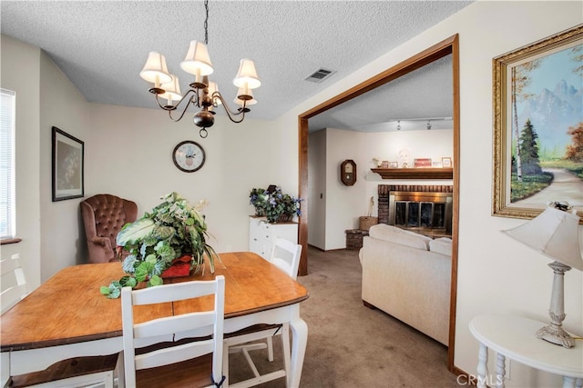 carpeted dining room with an inviting chandelier, a textured ceiling, and a brick fireplace