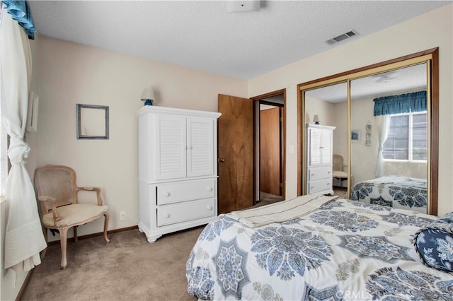 bedroom with a textured ceiling, carpet, and a closet