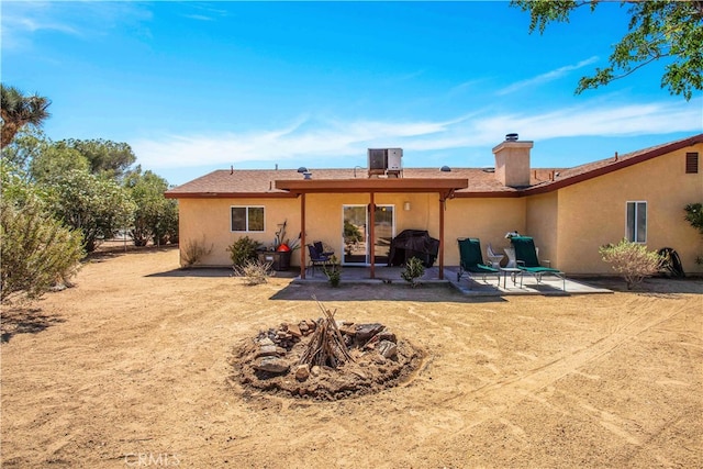 rear view of house with a patio, an outdoor fire pit, and central air condition unit