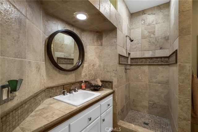 bathroom featuring tasteful backsplash, vanity, and tiled shower