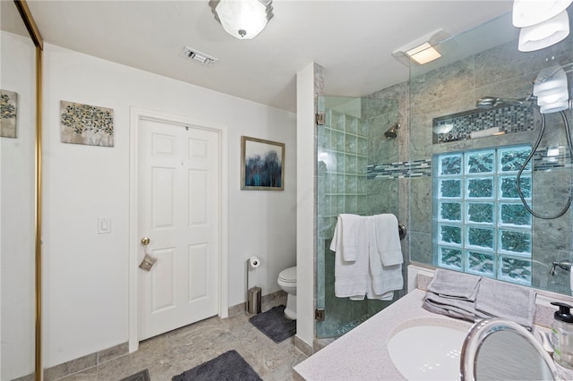 bathroom with toilet, vanity, and tiled shower