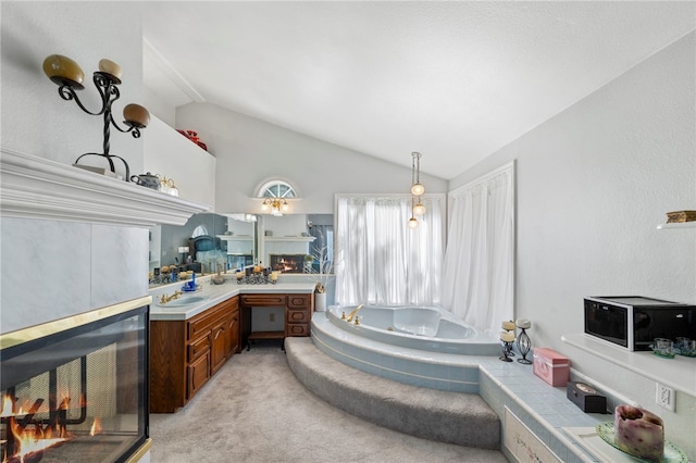 bathroom with vanity, a bath, and lofted ceiling