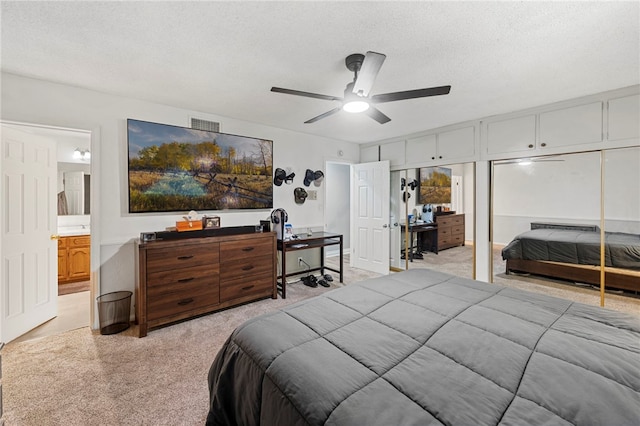 carpeted bedroom featuring ceiling fan, a textured ceiling, and ensuite bath