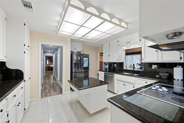 kitchen with a center island, dark stone counters, sink, white cabinetry, and stainless steel appliances