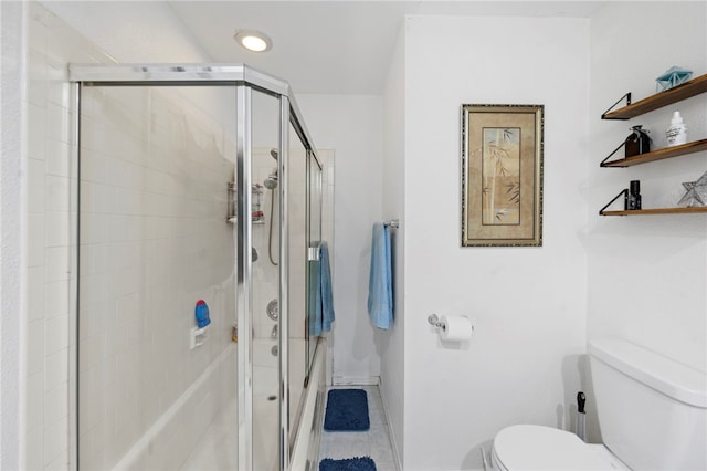 bathroom featuring a shower with door, tile patterned flooring, and toilet