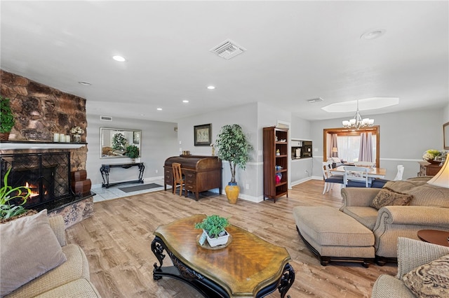 living room featuring a notable chandelier, light hardwood / wood-style floors, and a fireplace