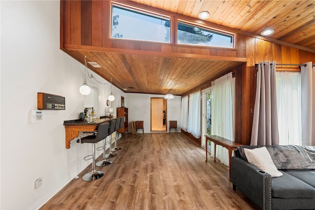 living room featuring wood-type flooring, wooden walls, wooden ceiling, and lofted ceiling