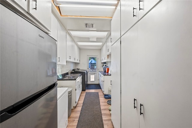 kitchen with hardwood / wood-style flooring, white cabinetry, sink, and stainless steel refrigerator