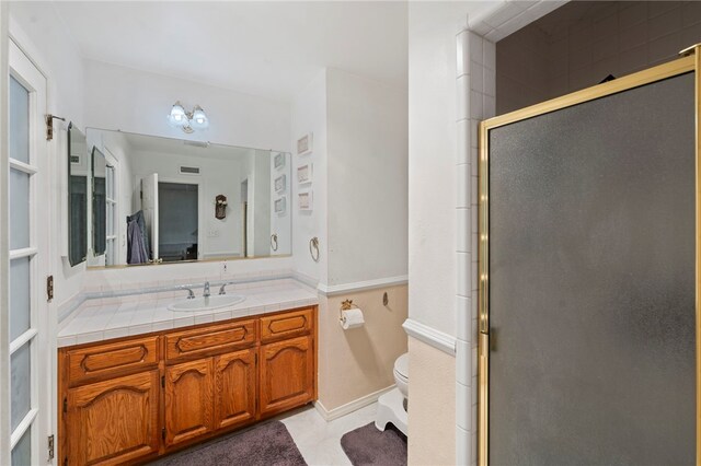 bathroom with vanity, toilet, and a shower with door