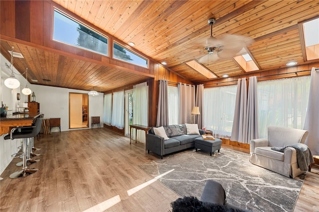 living room with lofted ceiling with skylight, ceiling fan, wood-type flooring, and wooden ceiling