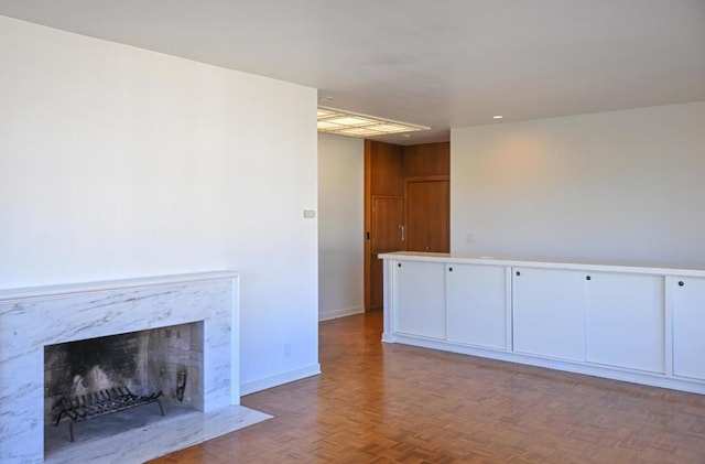 unfurnished living room featuring parquet floors and a high end fireplace