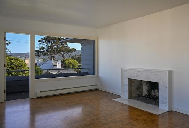 unfurnished living room featuring a healthy amount of sunlight, a fireplace, dark parquet flooring, and a baseboard heating unit