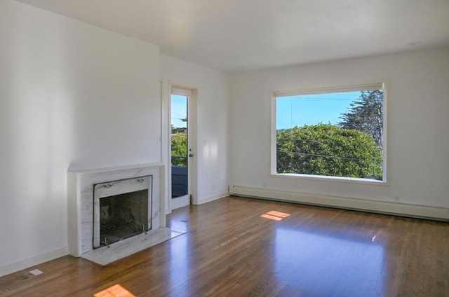 unfurnished living room featuring dark hardwood / wood-style floors, a high end fireplace, and baseboard heating