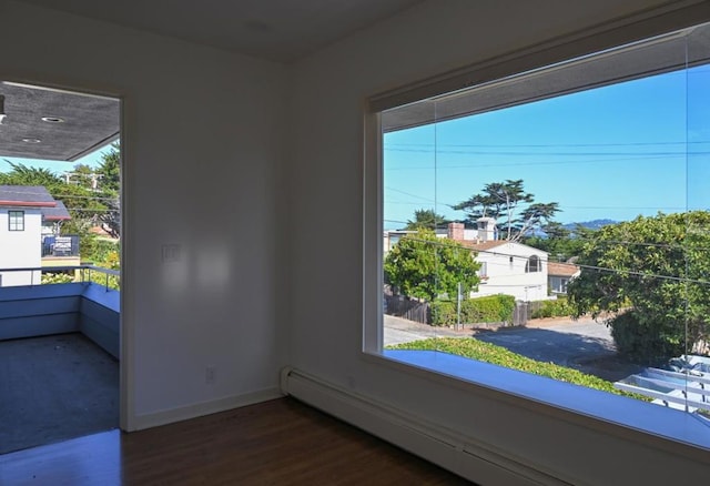 unfurnished room featuring a baseboard radiator and dark hardwood / wood-style floors