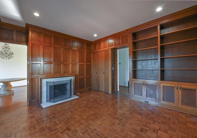 unfurnished living room featuring dark parquet flooring and wooden walls