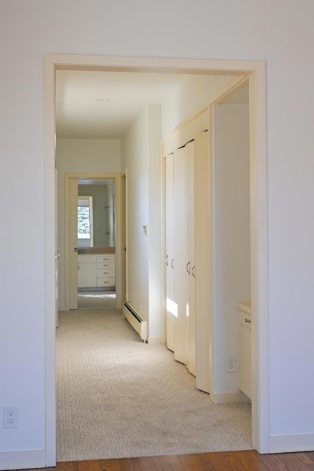 hallway with a baseboard radiator and light colored carpet