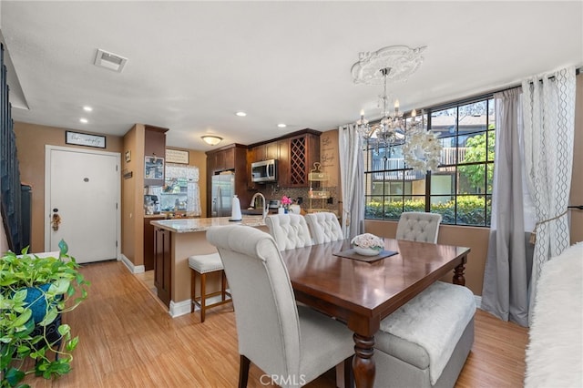 dining area featuring a notable chandelier and light wood-type flooring